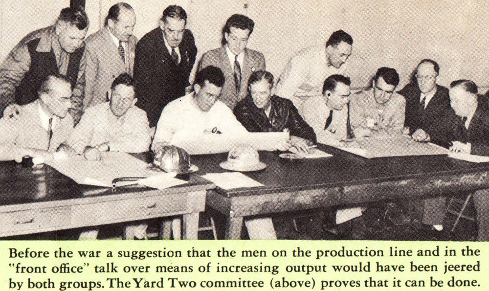 一群男人坐在和站在一张长桌子旁的照片