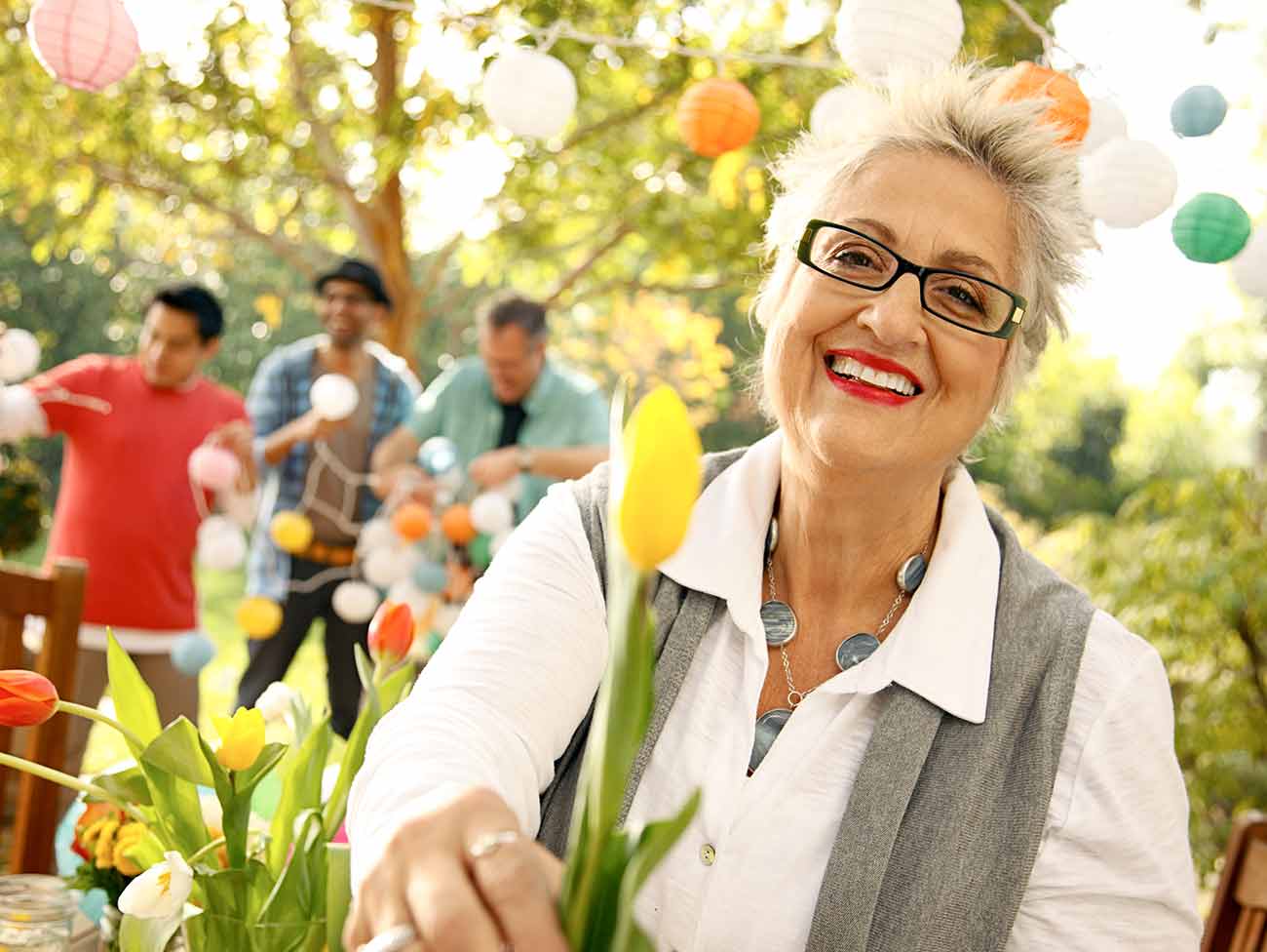 一位老妇人在外面的派对上拿着一朵黄色的郁金香