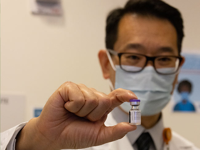 药房主任David Cheng安全地取出了一小瓶在加州注射的COVID-19疫苗。