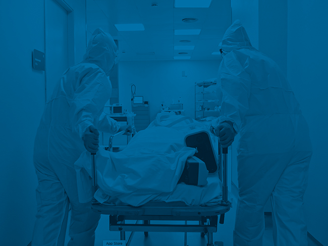一群身着个人防护装备的医务人员将病人推到轮床上。