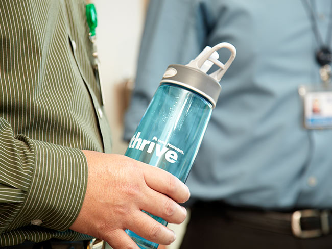 男人的手握着印有Thrive的水瓶