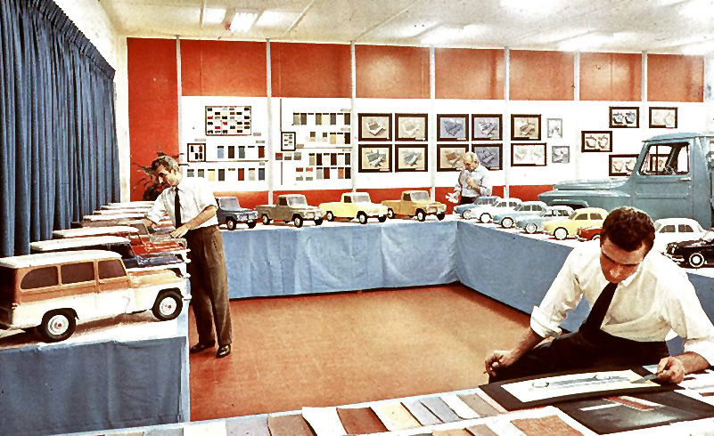 一名男子坐在展厅里，与微型吉普车模型坐在一起，检查插图