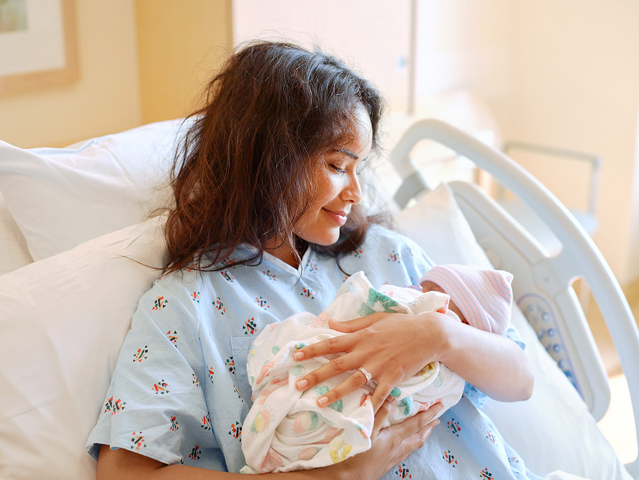 拿着新出生的婴孩的医院病床的妇女。