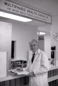 1966年，一名老年男性医生站在医疗机构的柜台上的照片。