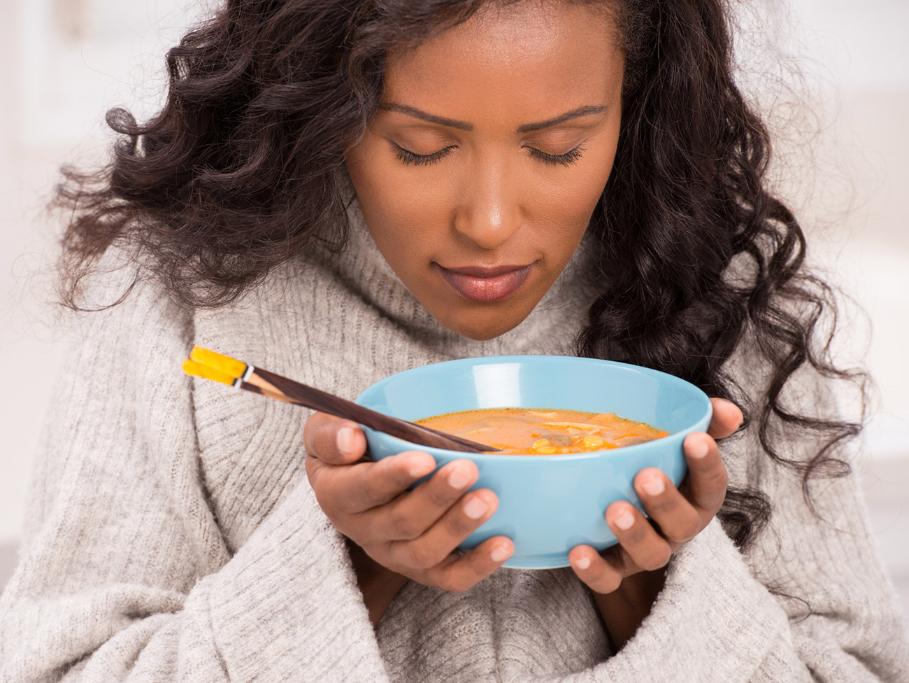 女人向下看一碗汤，她靠近脸