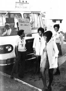 1970年代时代的黑人和白色照片，凯撒黑人学生护士协会的4个成员站在移动健康面包车前