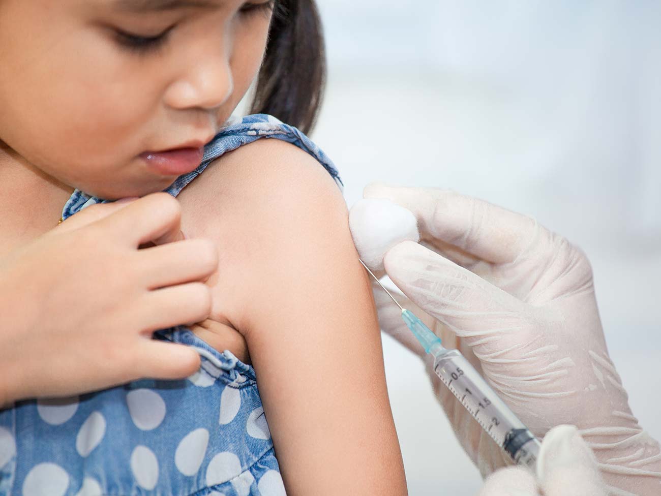 小女孩看着医生注射疫苗。