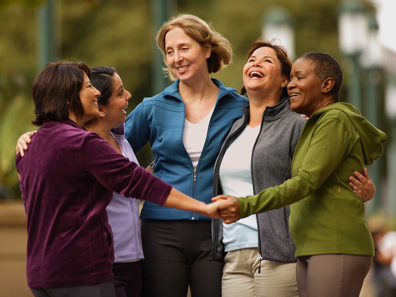 5个大笑的女人，站成一圈，手连在一起。