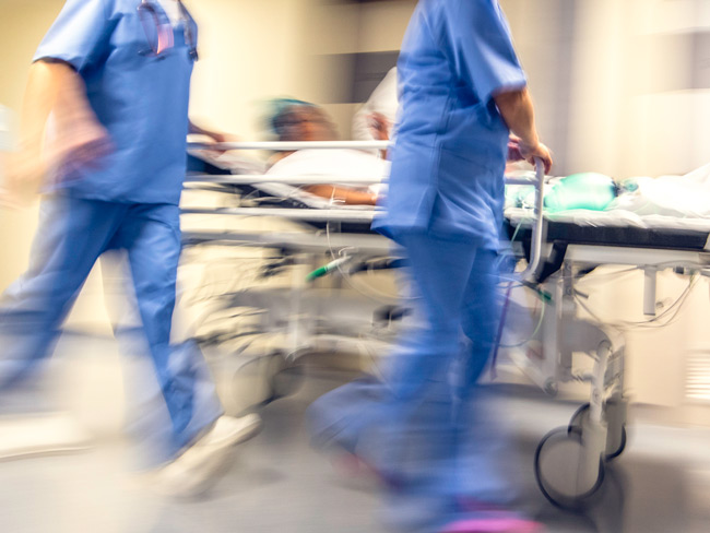 模糊的图像，医生和护士拉着医院轮床上的病人。