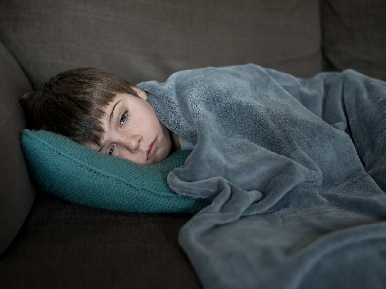 男孩的头戴在毯子下面的枕头上