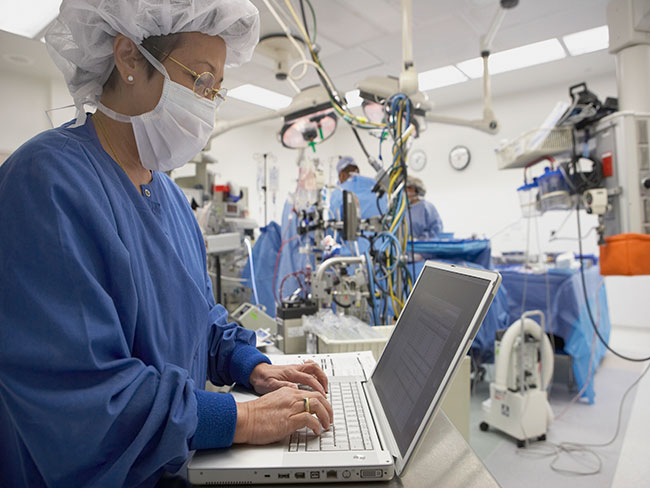 护士站在手术室的笔记本电脑前。