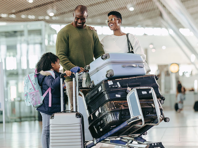 年轻幸福的一家人提着行李穿过机场