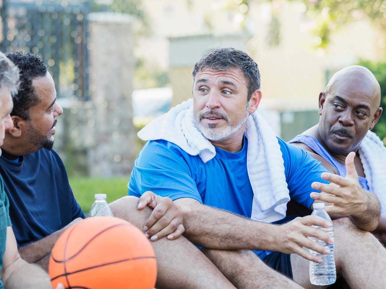 四个男人在室外篮球场坐着聊天