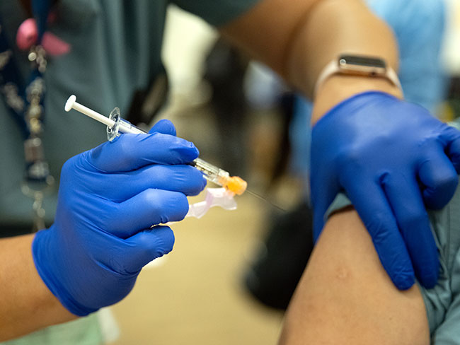 一名护理人员给一名成年人注射COVID-19疫苗
