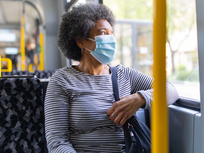一名妇女戴着防护口罩坐在公共汽车上
