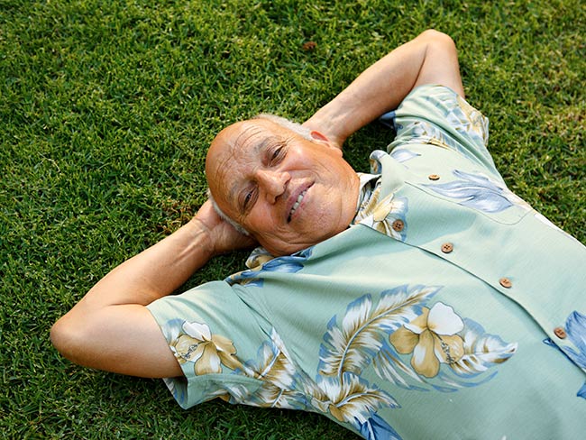 一个男人躺在草地上，双手放在脑后。
