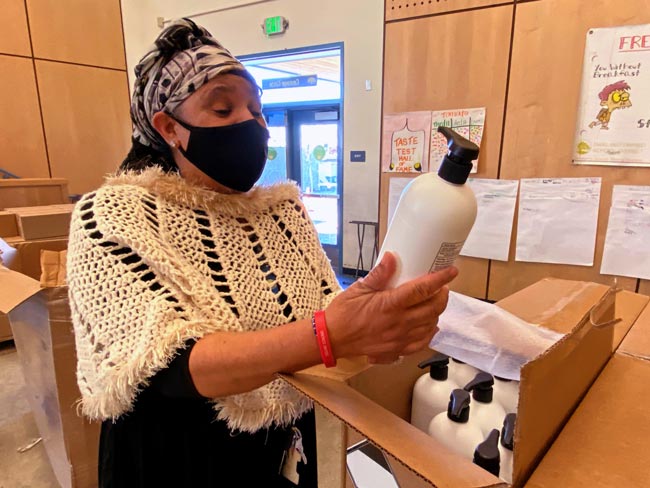 娜塔莎·摩尔戴着防护口罩，看着一瓶消毒剂。
