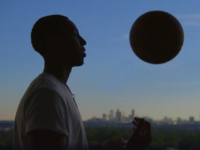 在城市天际线和昏暗天空的背景下，男人和篮球的剪影