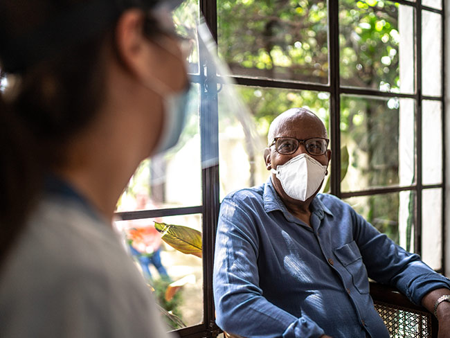 一位戴着口罩的老人正在和他的医生交谈。