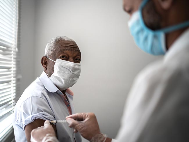 一个戴着保护性口罩的高级男子接受了19号疫苗接种。