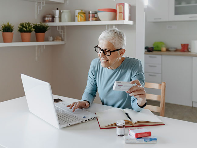 一位老年妇女用笔记本电脑在网上查找有关药物的信息。