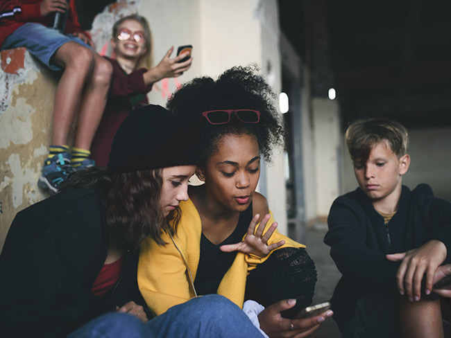 一群青少年坐在废弃建筑的室内使用智能手机