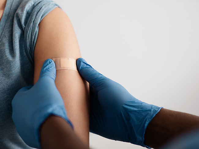 medical worker's gloved hands places bandage after vaccination