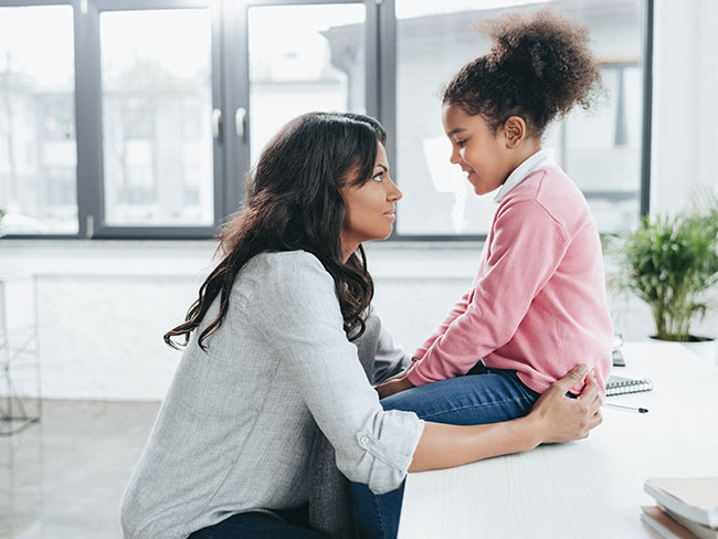 side view of african american mother talking with her daughter indoors