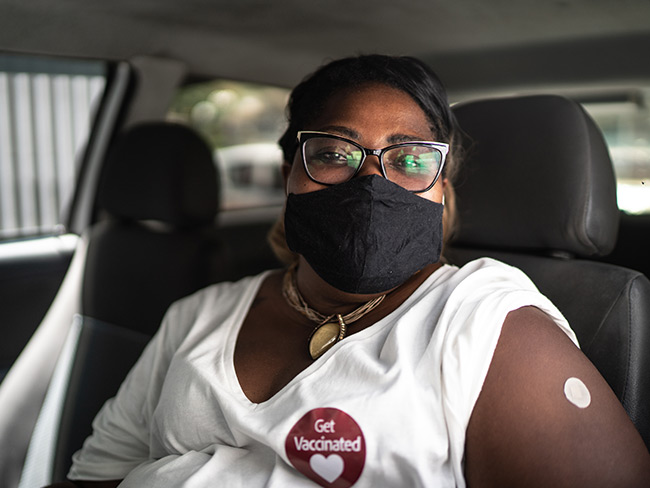妇女在Covid-19疫苗后在车上戴着口罩