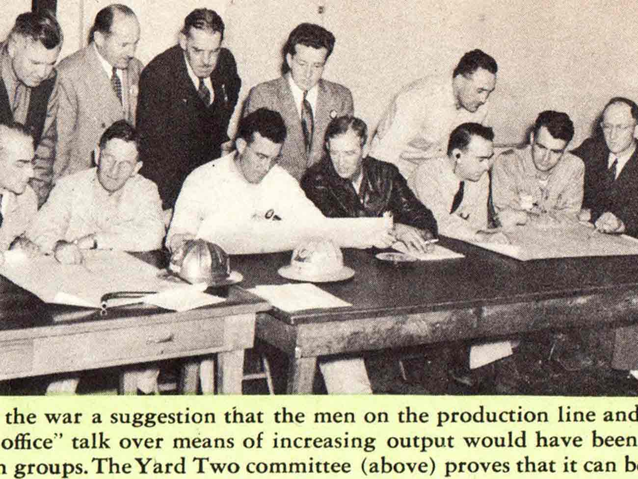 照片中的一群男人坐在或站在一张长桌旁