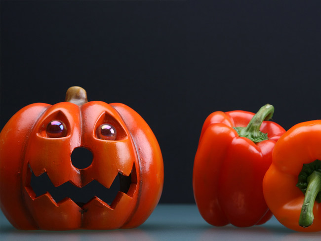 左侧装饰性杰克 - 奥兰特（Jack-o'-Lantern），右边有两个整个红色橙色辣椒。