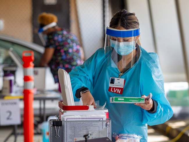 医务工作者穿着防护装备和服用疫苗的容器