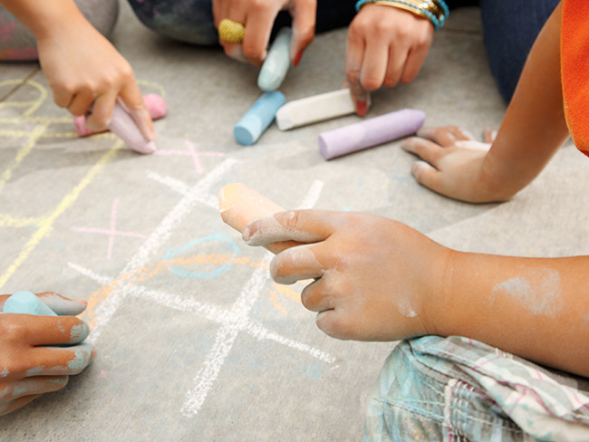 children drawing on concrete using chalk