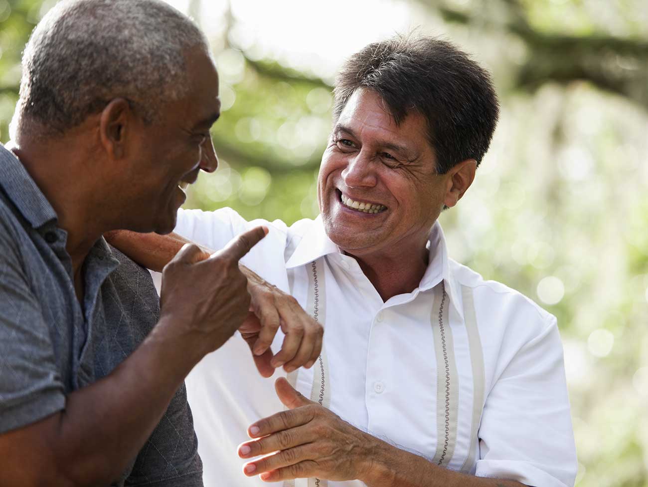 Multi-ethnic men sitting outdoors, having conversation.