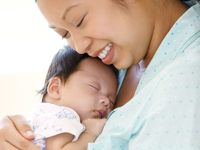 一位微笑的母亲抱着她刚出生的婴儿。