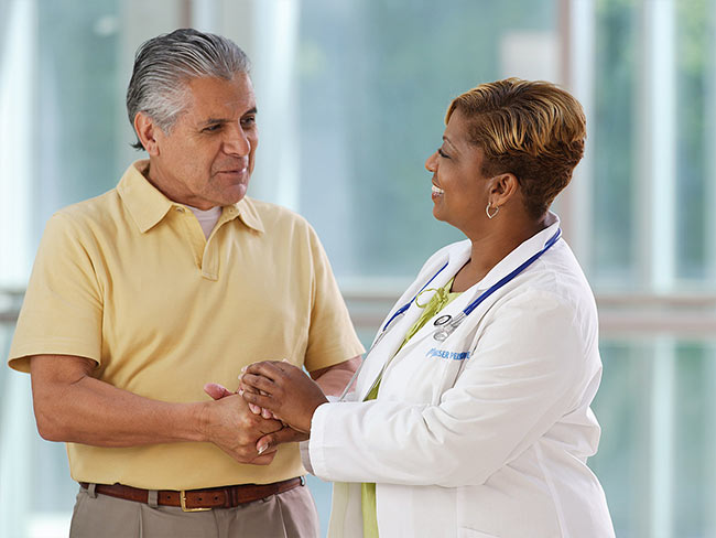 一位面带微笑的女医生正在和年长的男病人握手。