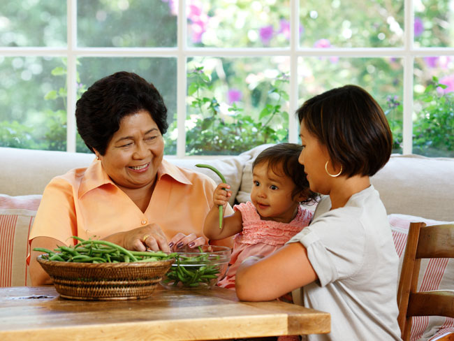 祖母、母亲和孙女坐在桌旁串青豆