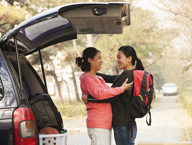 Mother and daughter embracing near a car