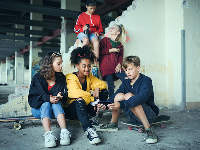 组的青少年在一个废弃的建筑,使用智能手机。