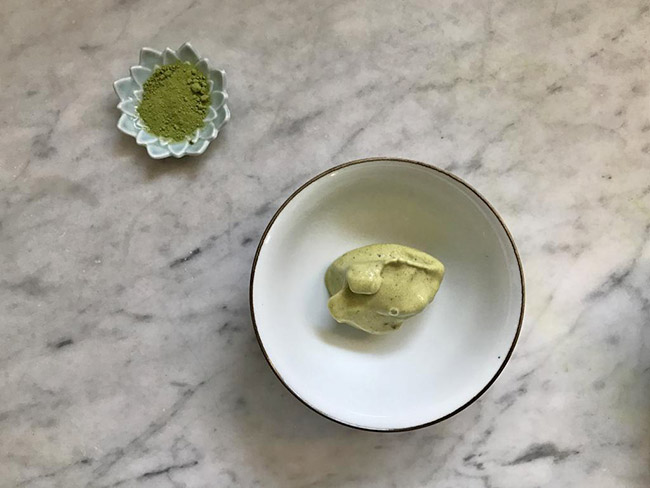 大理石柜台上放着一小碗绿色的冷冻甜点。