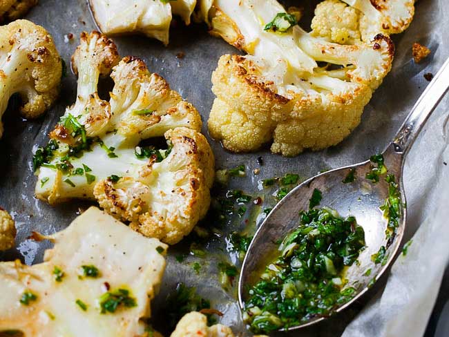 Cauliflower steaks with green sauce and a spoon