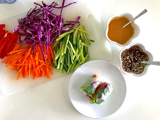 越南新鲜春卷配彩虹蔬菜和豆腐放在白色盘子里，旁边放着各种各样的蔬菜丝。